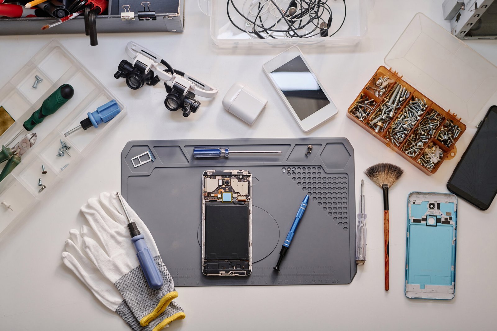 Disassembled smartphone displayed on repairman table surrounded by tools and professional equipment